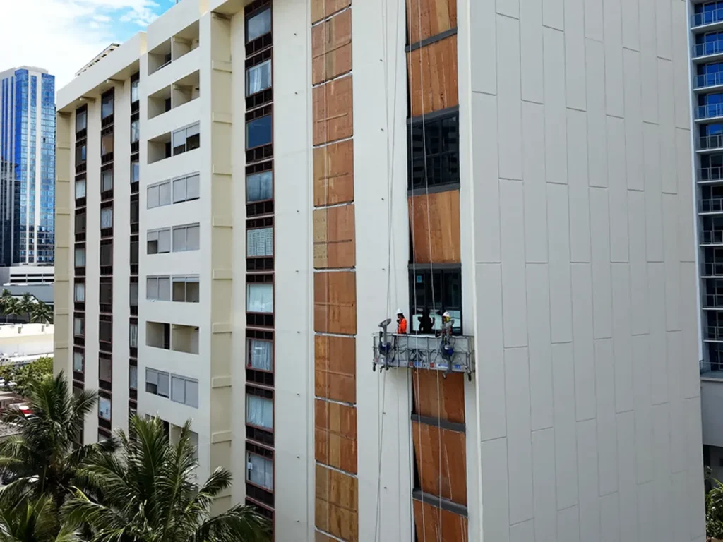 Structural Systems Hawaii crew on swing stage performing commercial window replacement at high-rise building